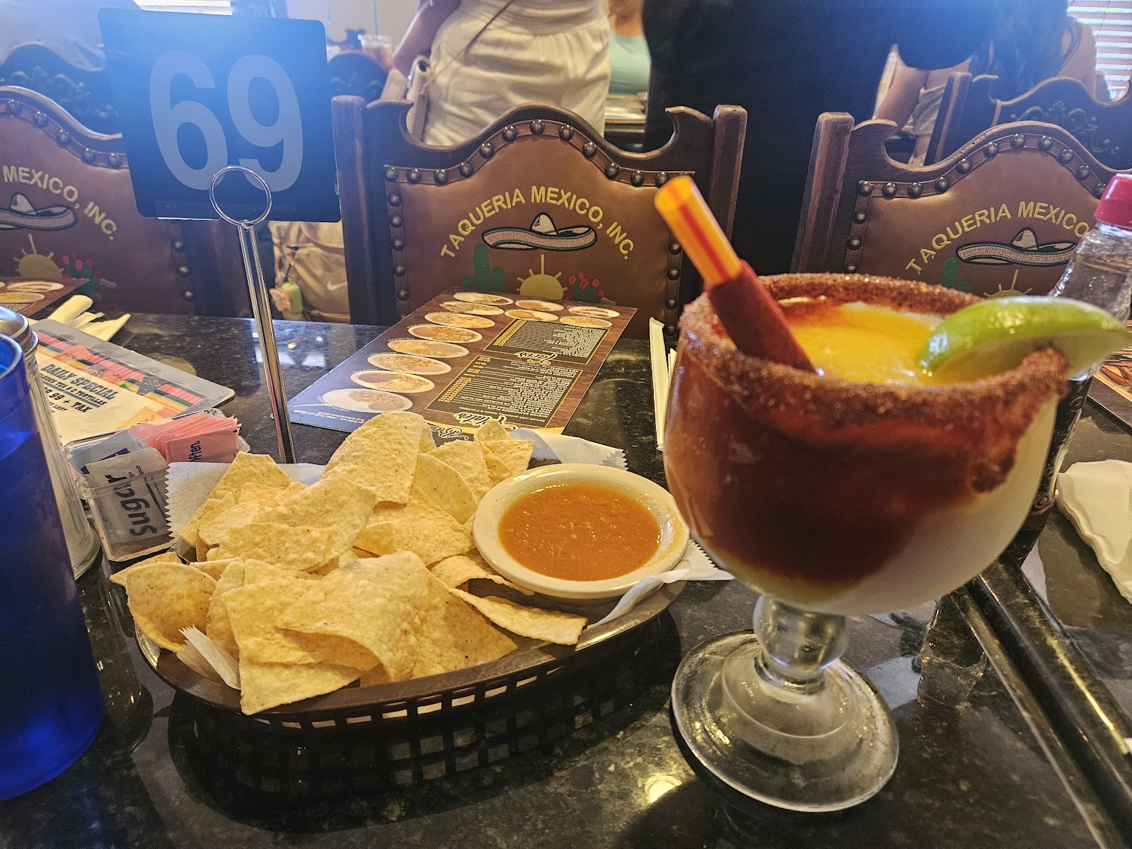 Michelada with chili-salt rim next to chips and salsa on the bar